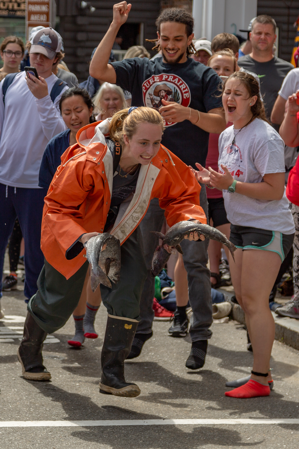 Student running outside with fish. People cheering in the background.