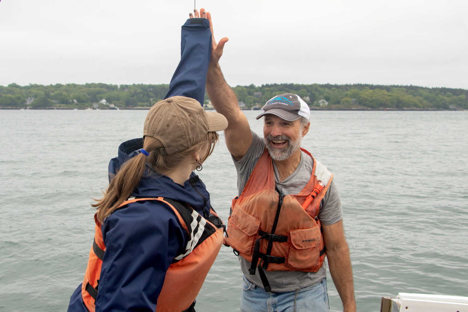 Scientist and student on boat highfive.