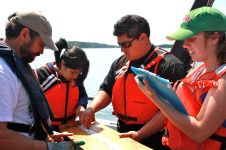 Instructor and students outside by water performing an experiment