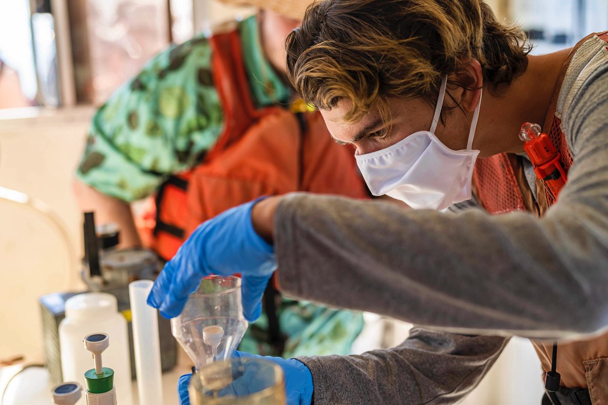 student in a lab with collected samples