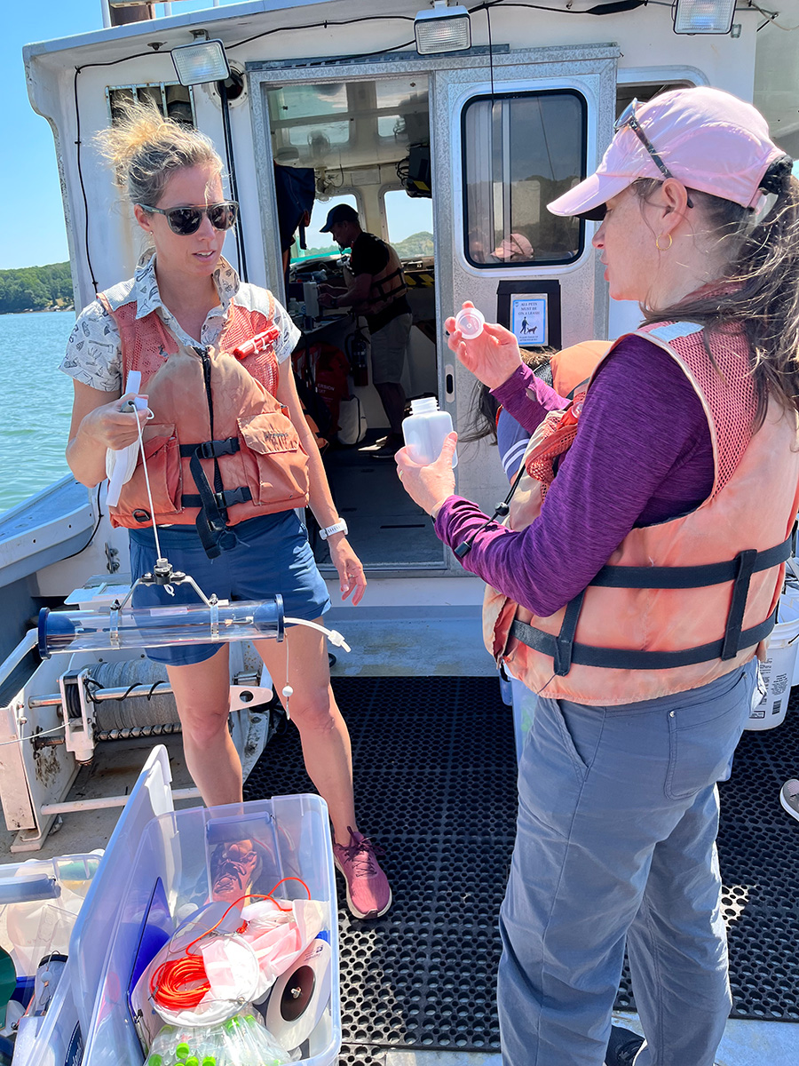 2 females on a boat preparing to gather samples from the ocean