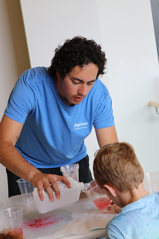 PhD student Kyle Oliveira giving a demonstration to a young scientist