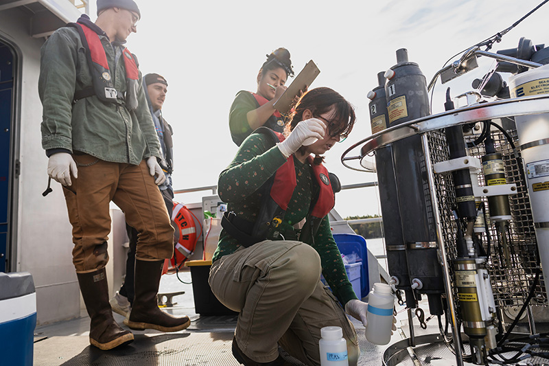 students gathered around an instrument designed to collect water samples from different depths