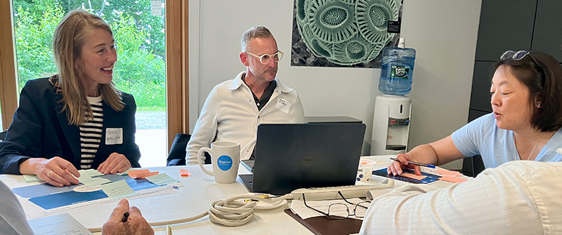 Three people sitting at a table with papers and a laptop