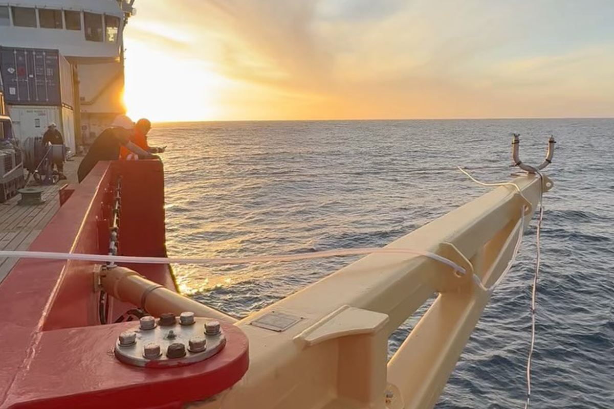 Crew members collaborate on deck at sunset